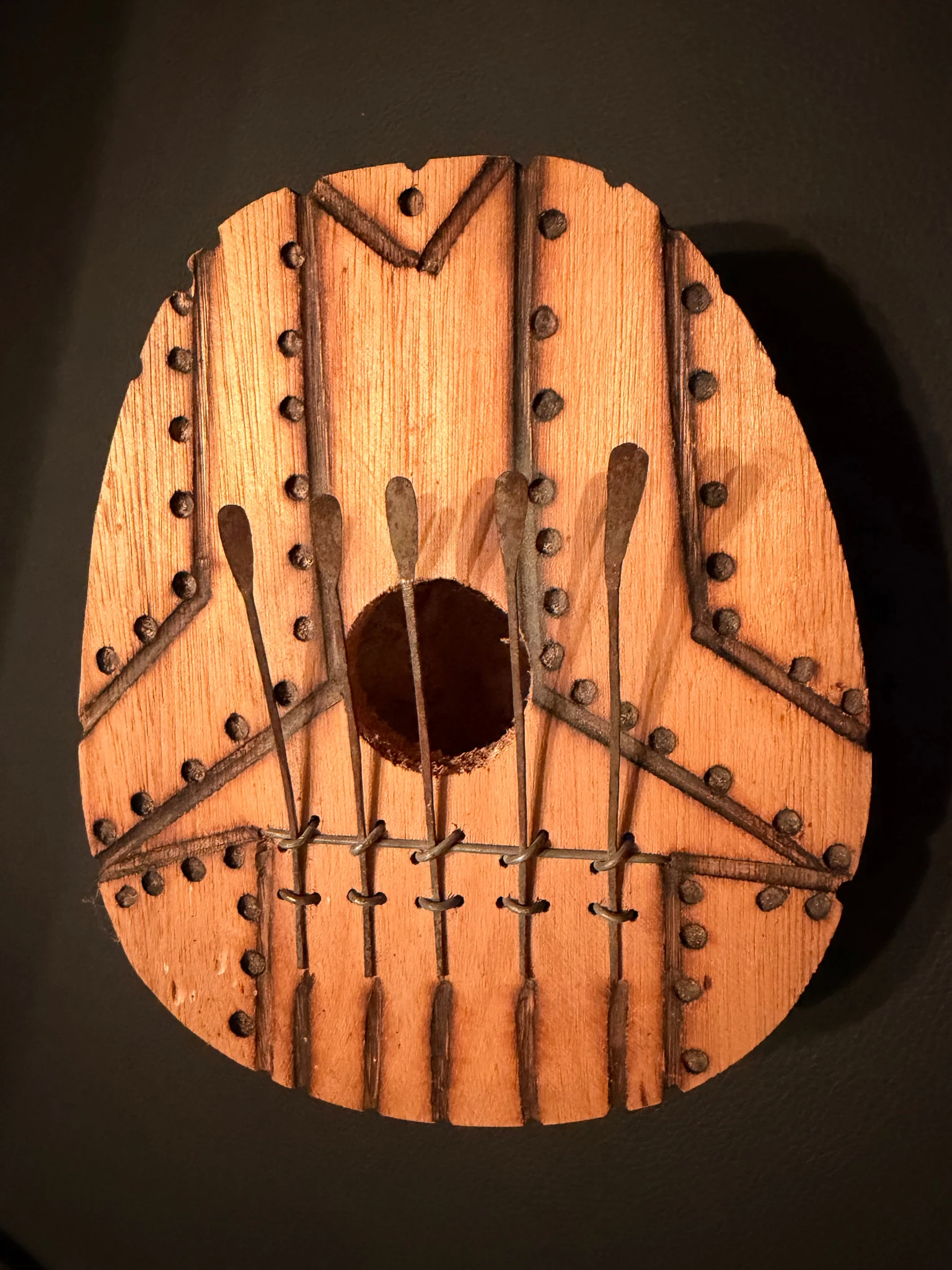 A circular wooden Ping Pang travel kalimba with five metal tines, a central sound hole, etched lines, and burned-dot markings
